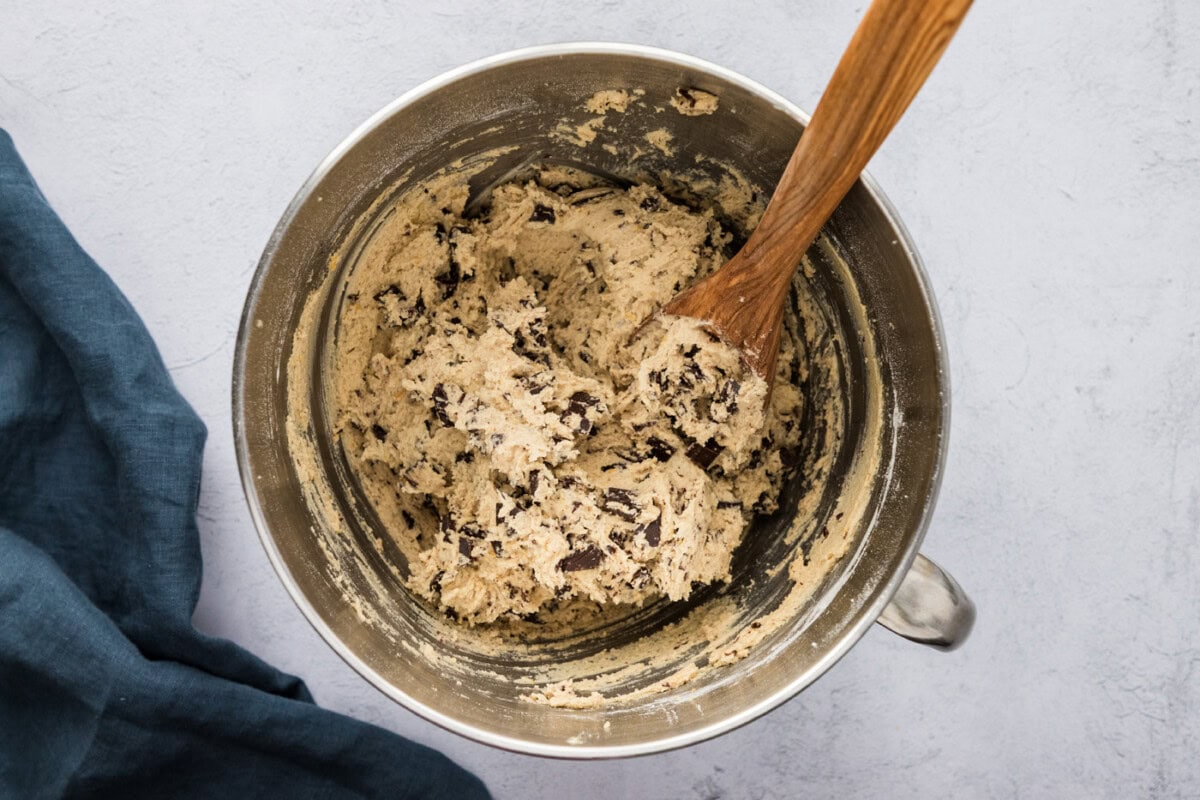 orange chocolate chip cookie dough in a stand mixer with a wooden spoon