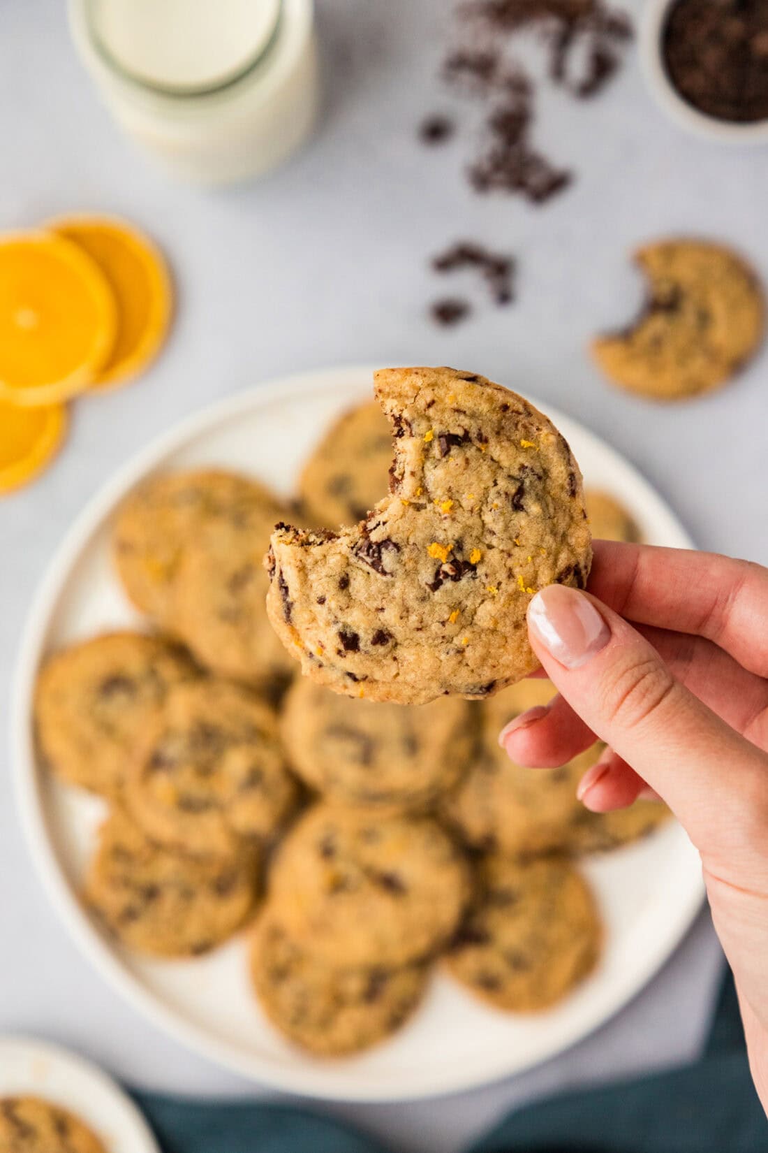 Hand holding a Orange Chocolate Chip Cookie above a plate of cookies