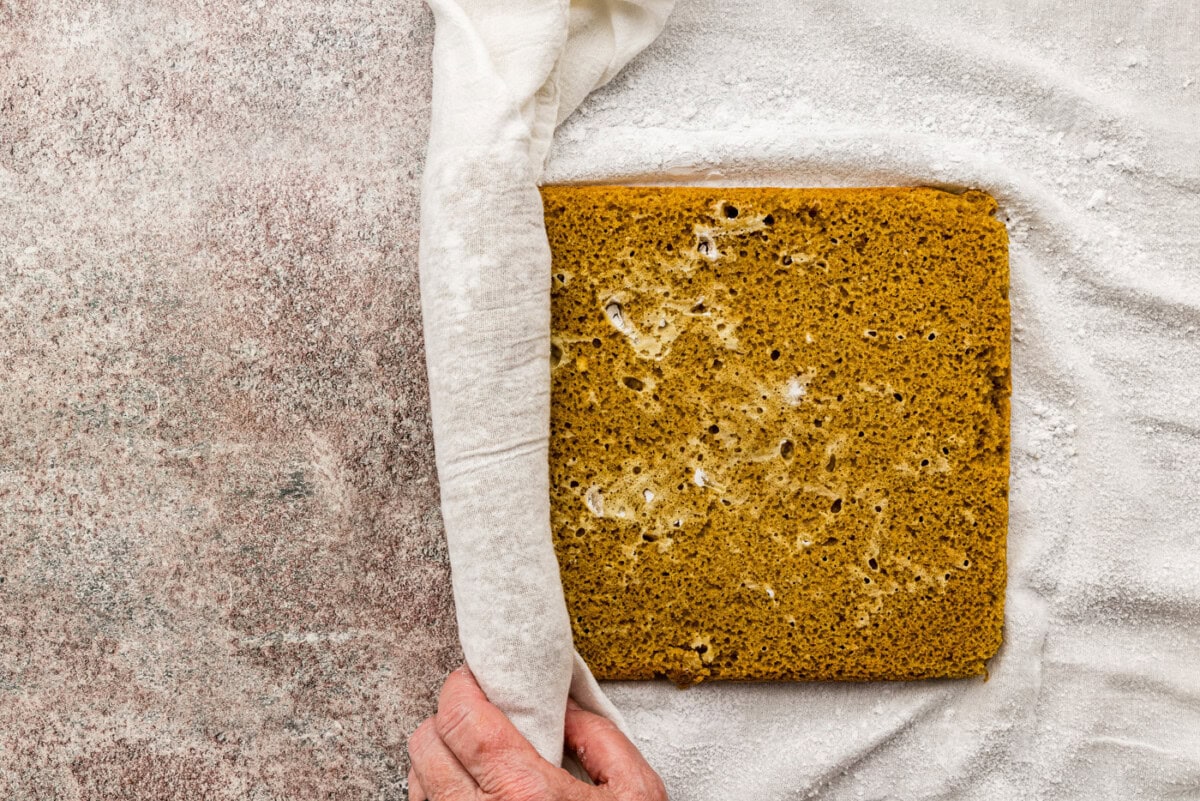 gently rolling pumpkin cake up into a kitchen towel