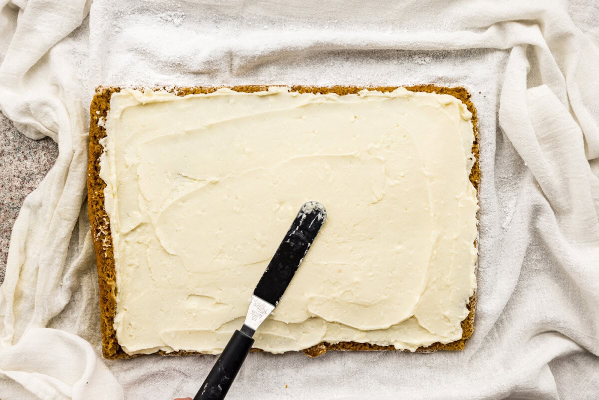 spreading cream cheese frosting over cake with an offset spatula