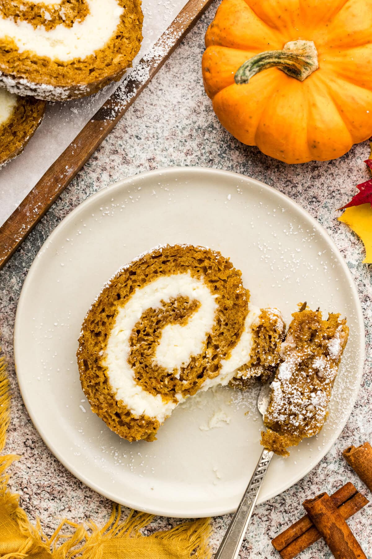 Slice of Pumpkin Cake Roll on a plate with a bite removed