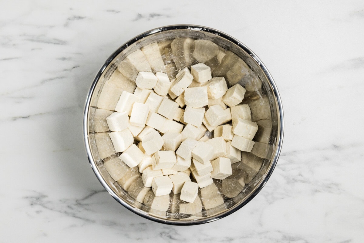 tofu cubes in a mixing bowl tossed in cornstarch