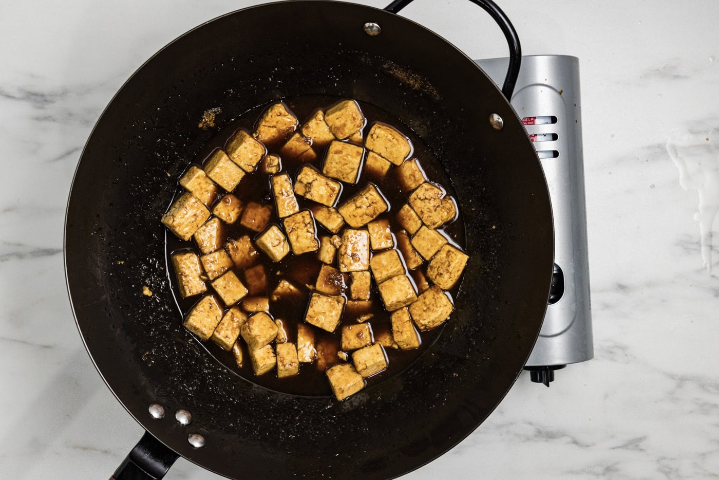 stir fried tofu in a wok with teriyaki sauce