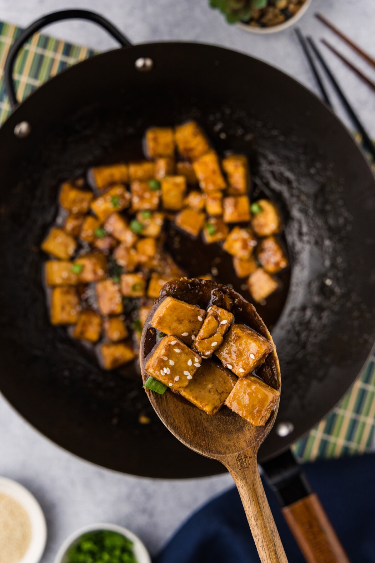 Spoonful of Teriyaki Tofu held above a wok of Teriyaki Tofu