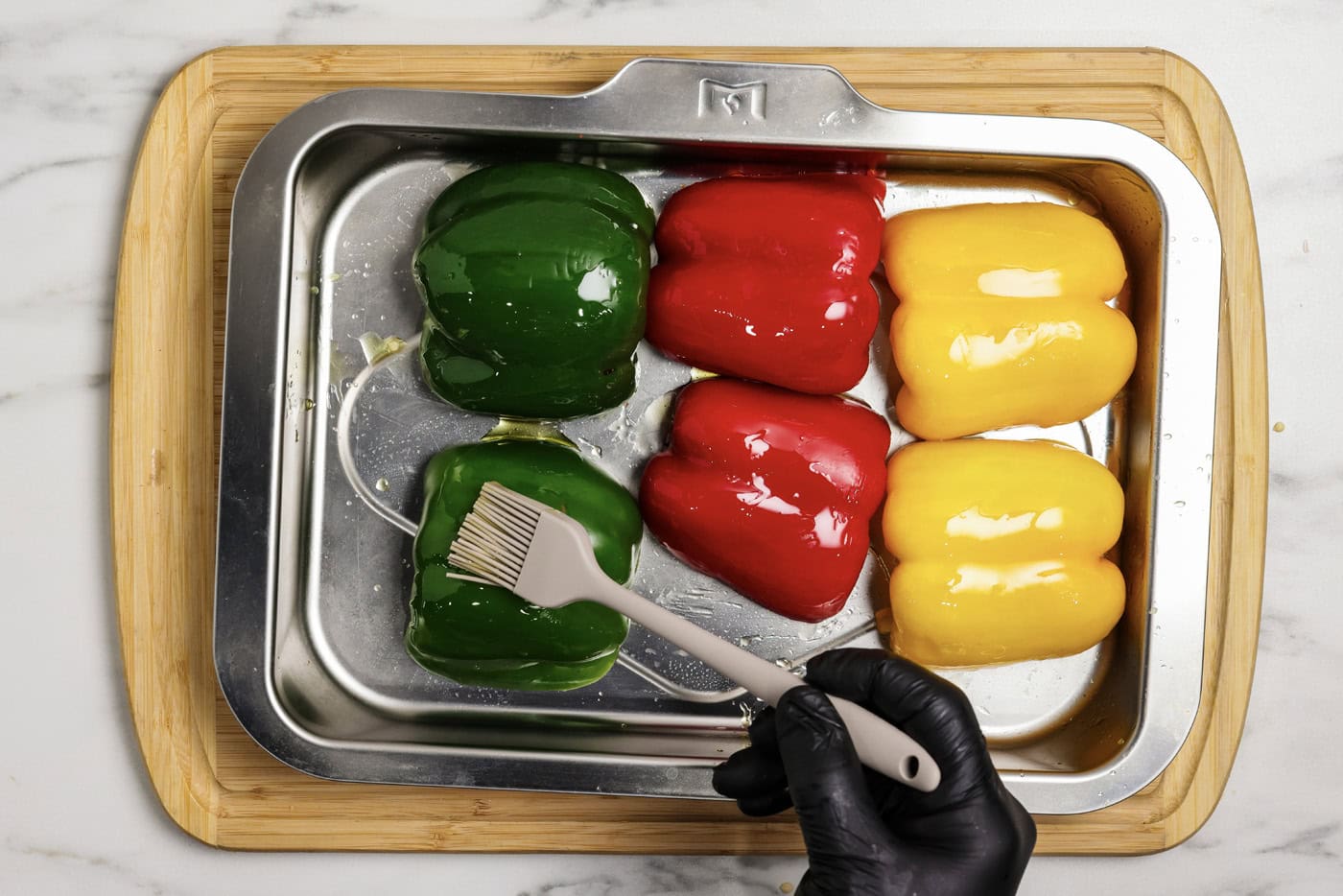 brushing bell peppers halves with olive oil on a baking sheet