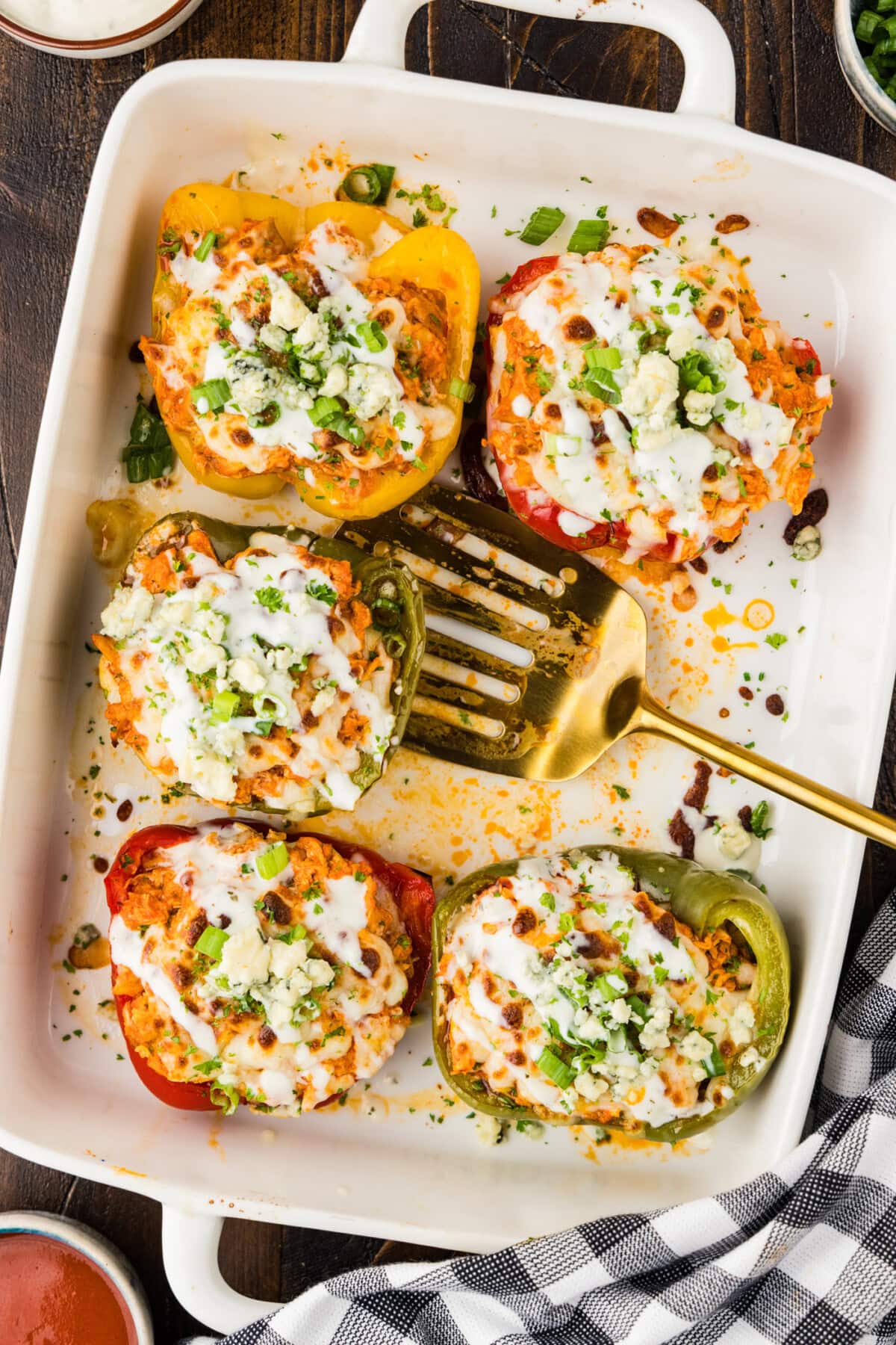 Five Buffalo Chicken Stuffed Peppers in a dish with a spatula