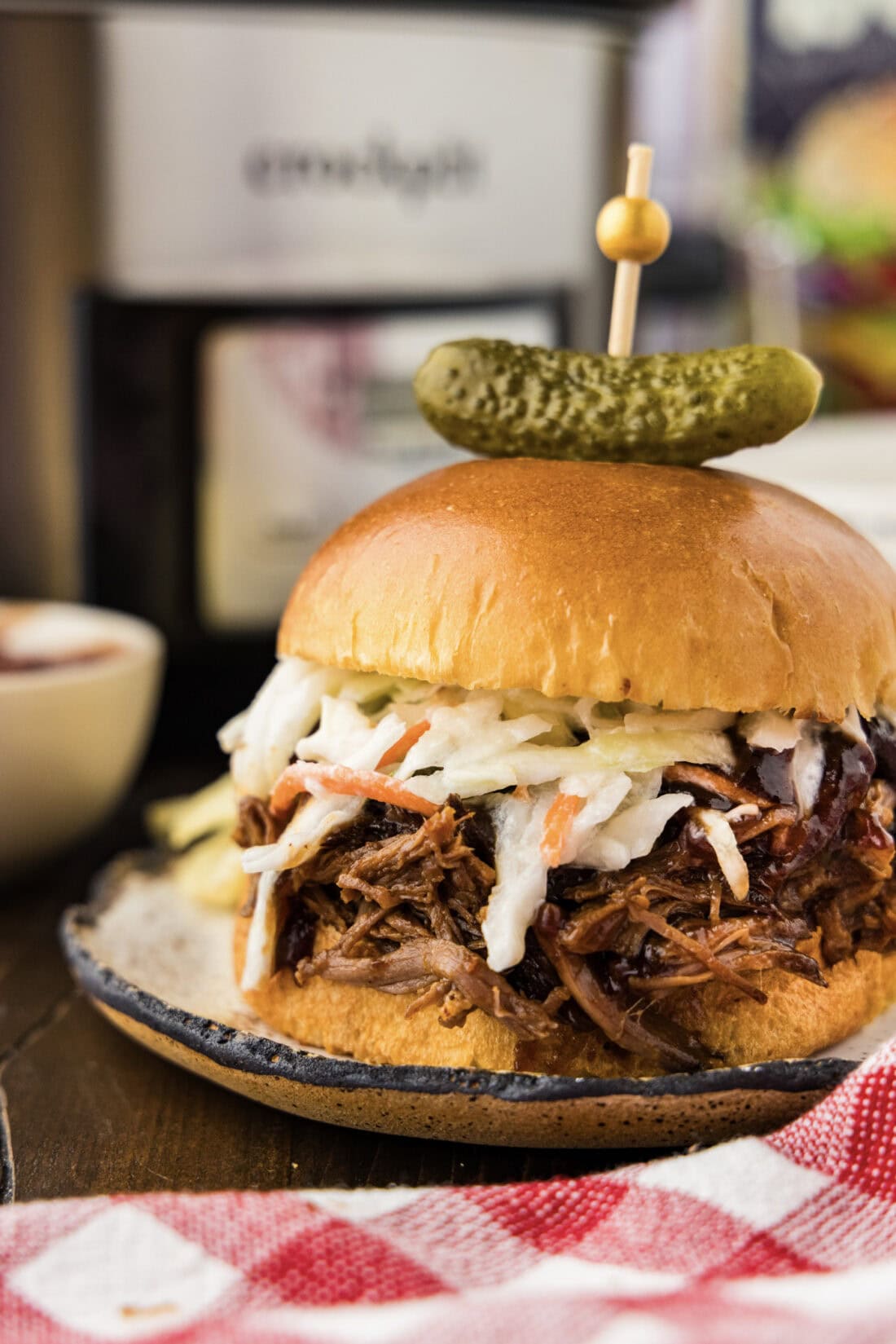Close up photo of a Crockpot BBQ Beef Sandwich with a pickle on top