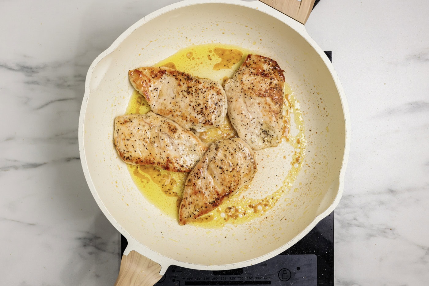 chicken breasts cooked in a skillet until golden