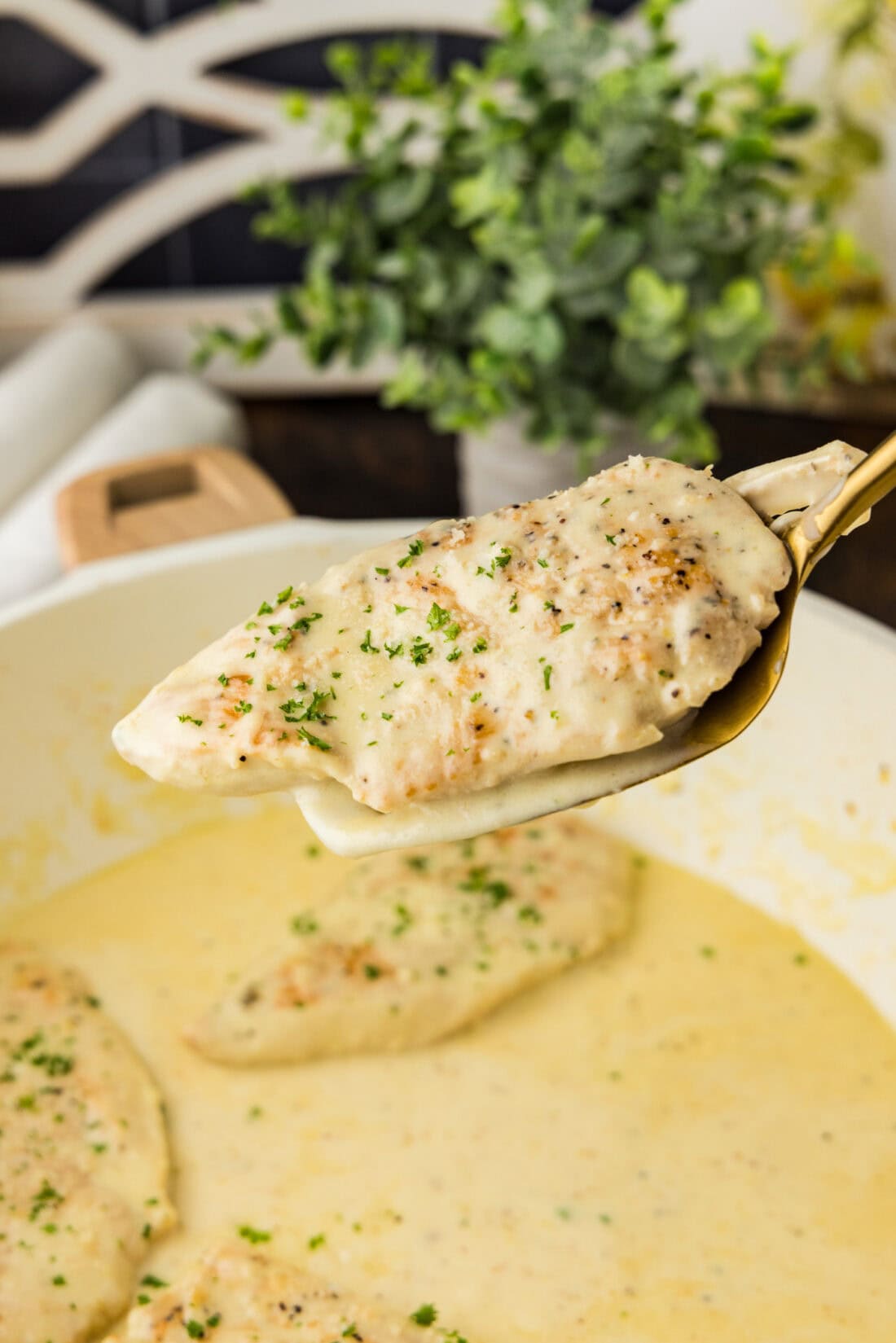 Garlic Parmesan Chicken on a spatula held above a skillet of Garlic Parmesan Chicken