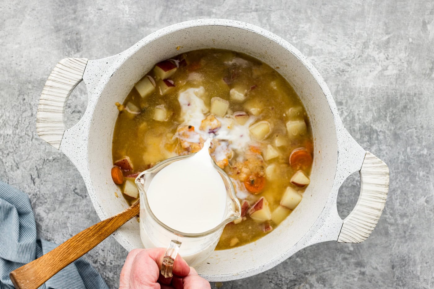 Pouring milk into Dutch oven with potato soup mixture