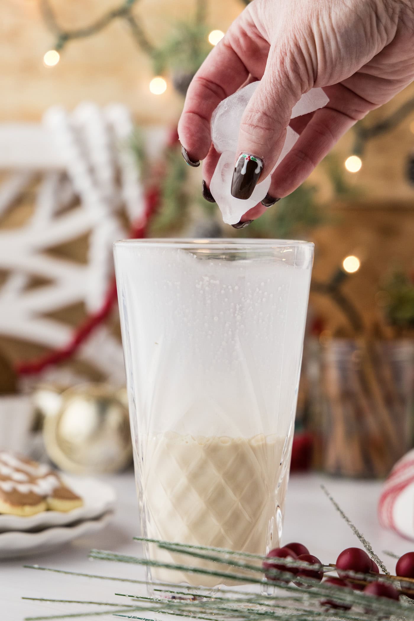 hand adding ice to a cocktail shaker with liquid