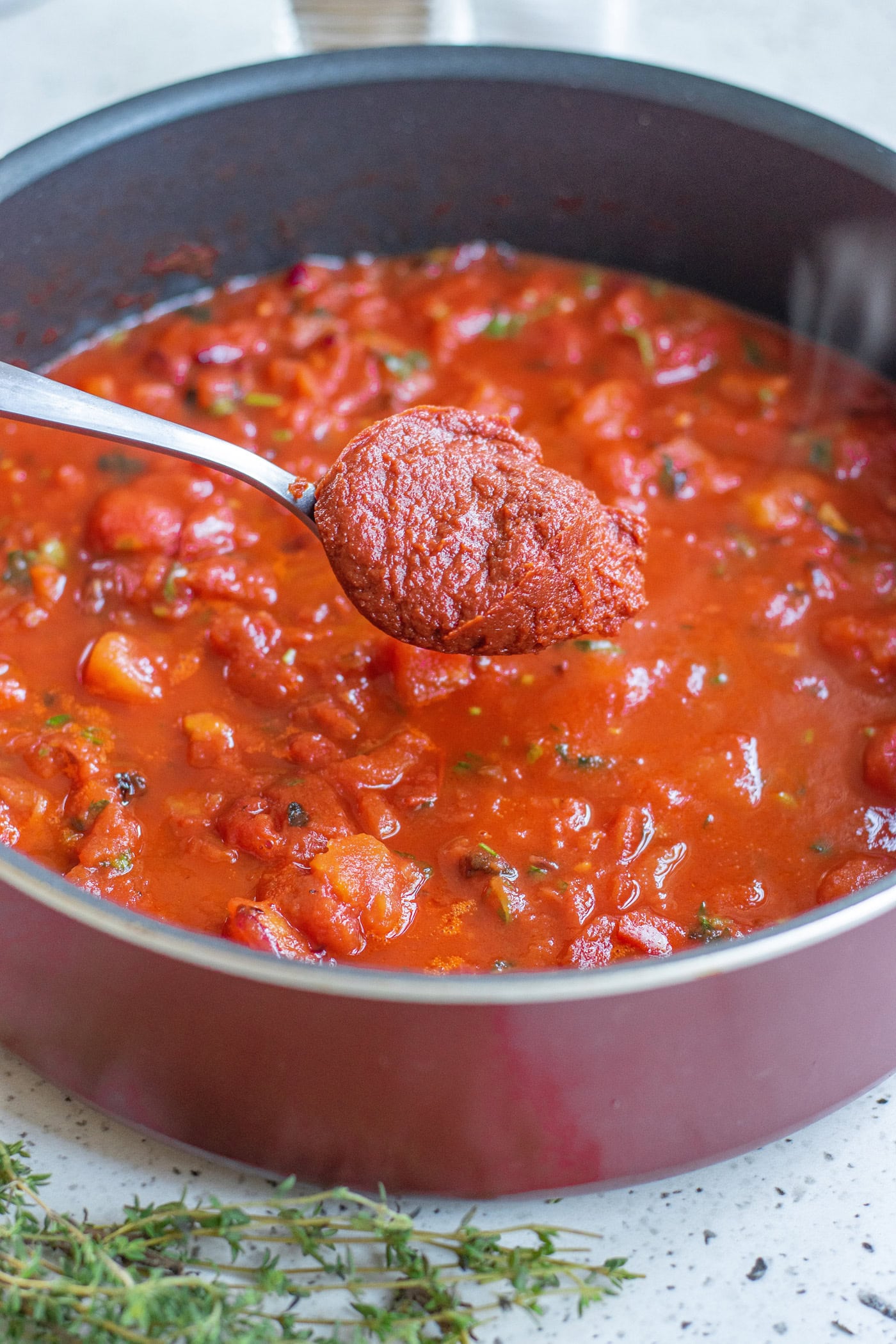 spoonful of tomato paste of a pot of marinara sauce
