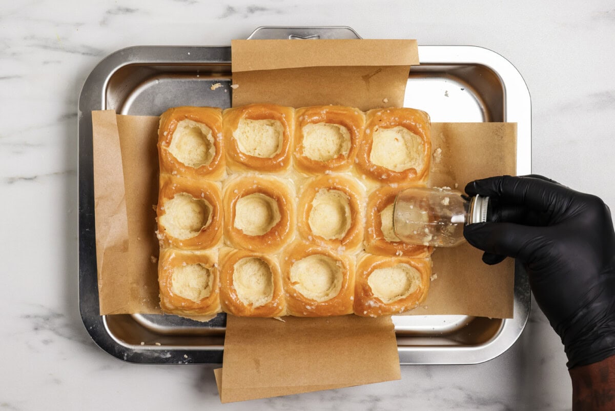 hand using a mason jar to create even holes inside bread rolls