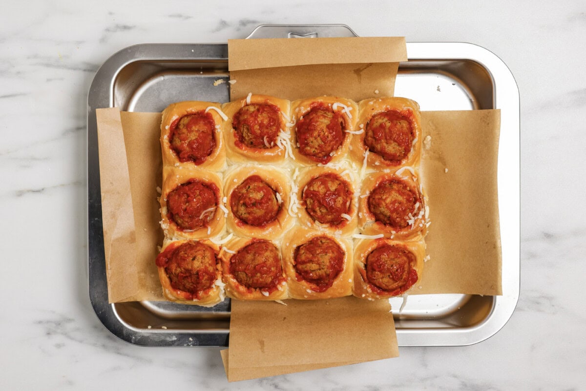 meatball and marinara sauce added on top of cheese and dinner rolls