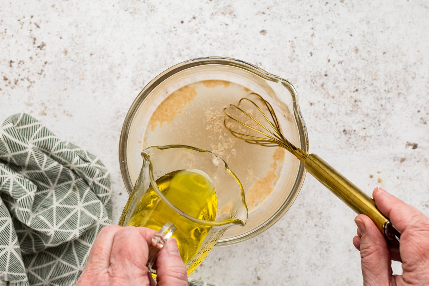 Whisking olive oil into yeast and water mixture in a bowl