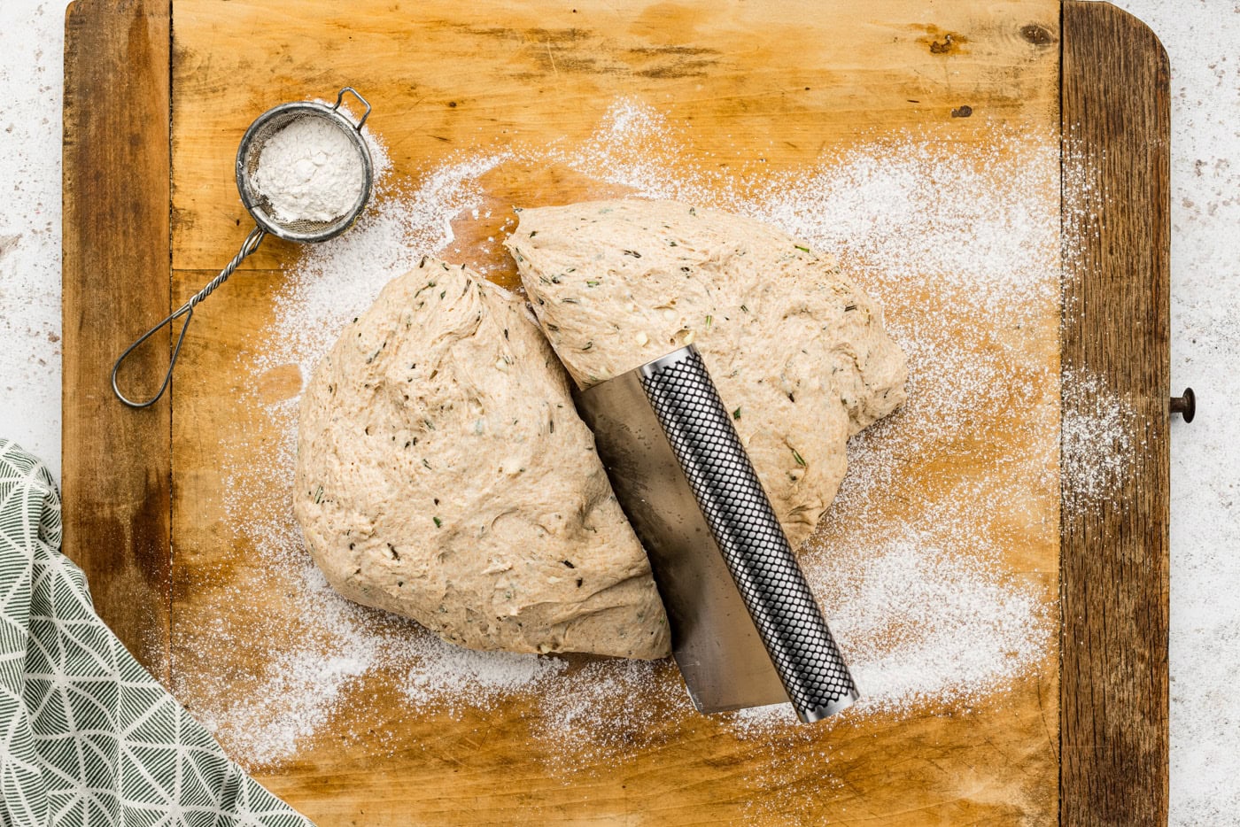 cutting bread dough ball in half on a cutting board