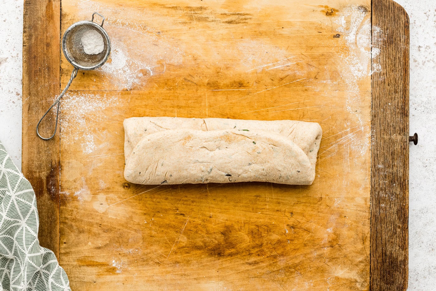 bread dough rolled up tightly on a cutting board