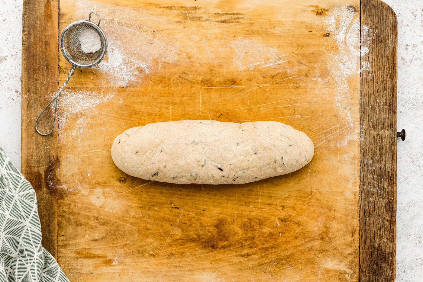 garlic rosemary bread dough shaped on a cutting board