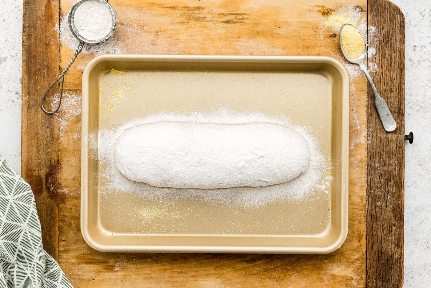 flour dusted on top of rosemary garlic bread dough on a baking sheet