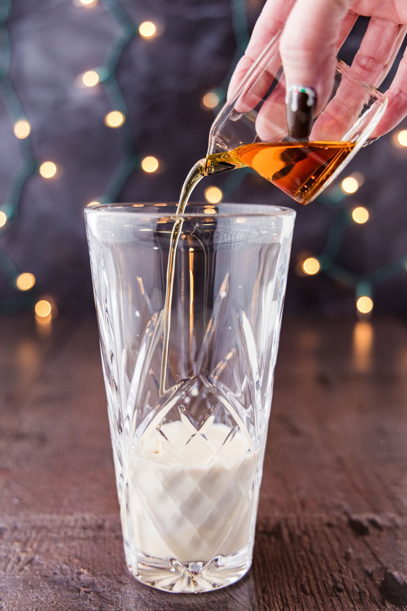 pouring amaretto into a cocktail shaker glass