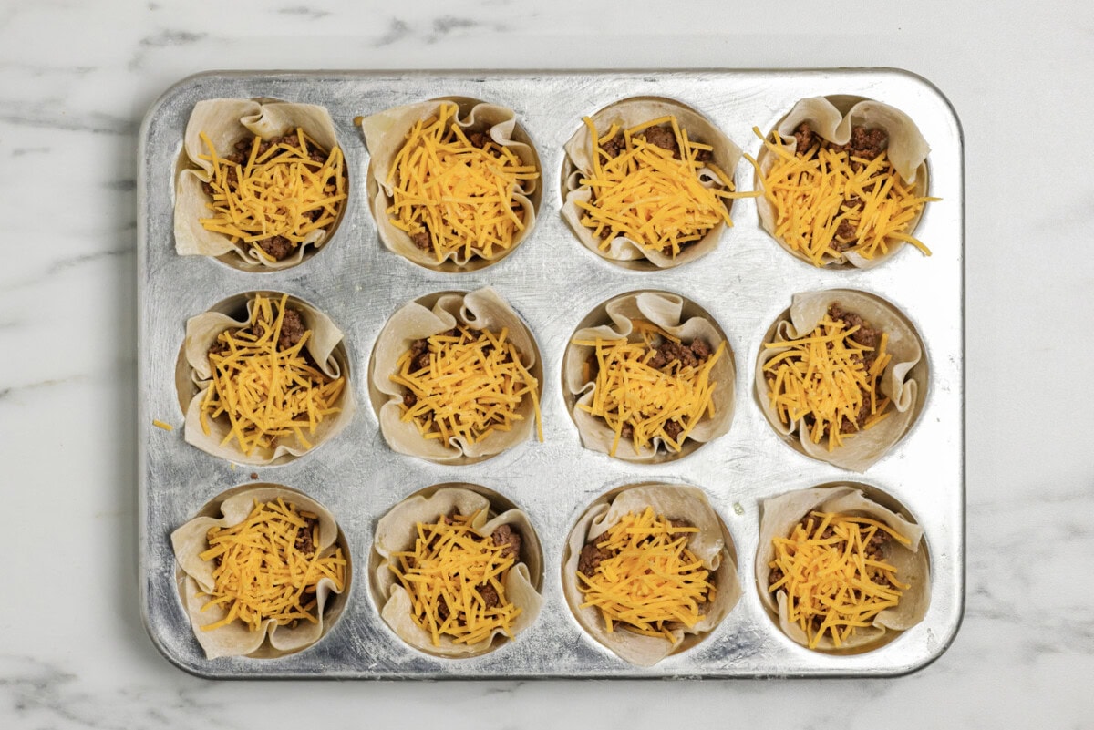 Shredded cheese added on top of the taco meat inside wonton wrappers