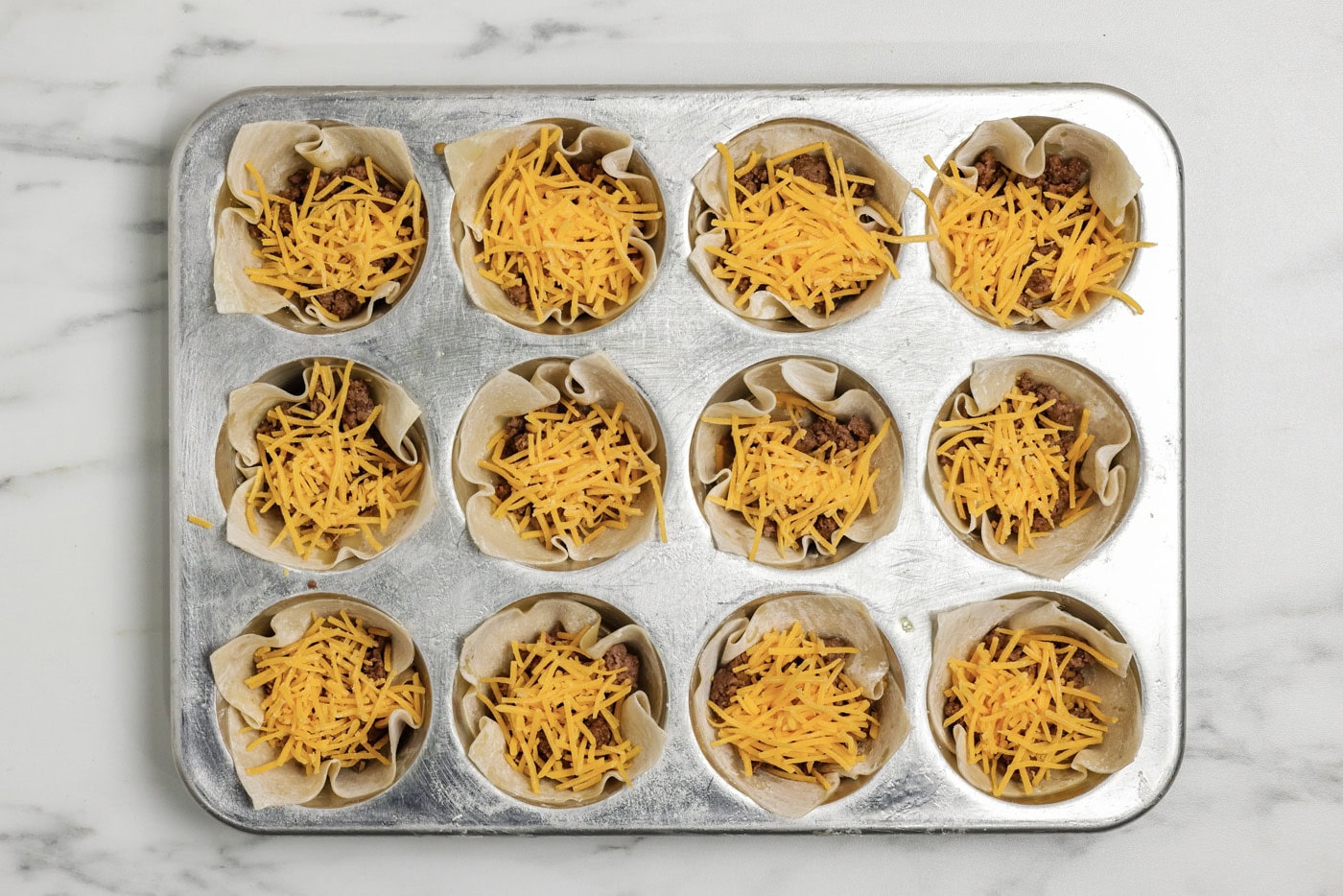 Shredded cheese added on top of the taco meat inside wonton wrappers