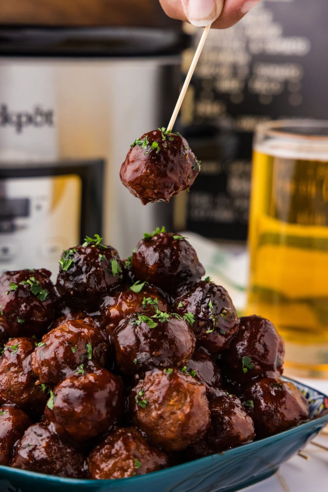 BBQ Meatball on a toothpick held above a pile of BBQ Meatballs