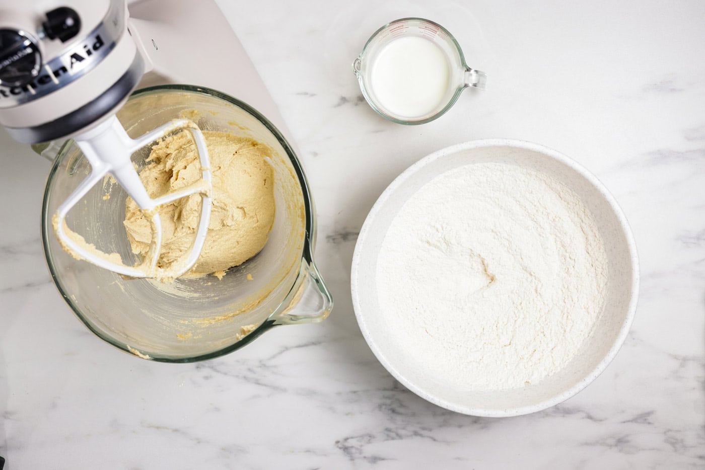 Flour mixture next to cookie dough in a stand mixer