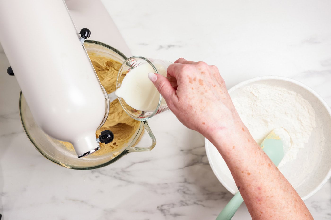 Pouring buttermilk into cookie dough in a mixer