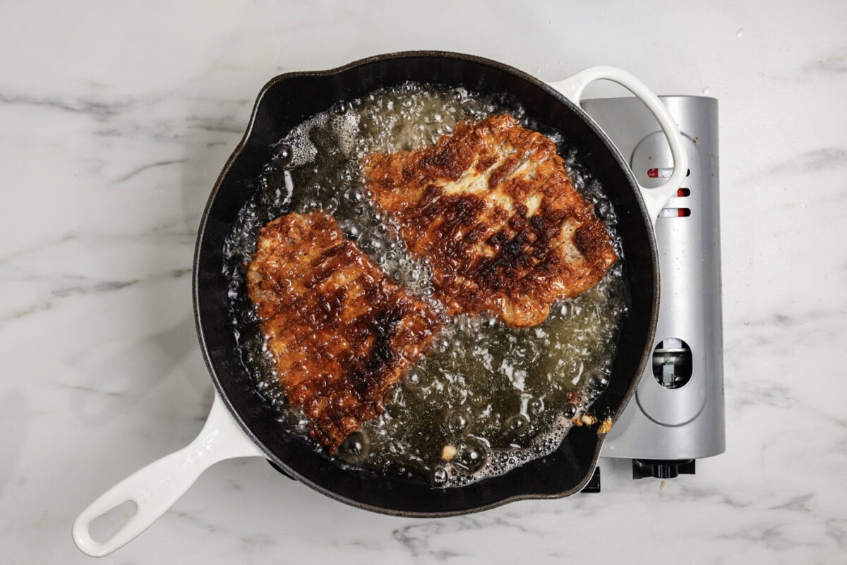 Chicken fried steak cooking in oil in a skillet