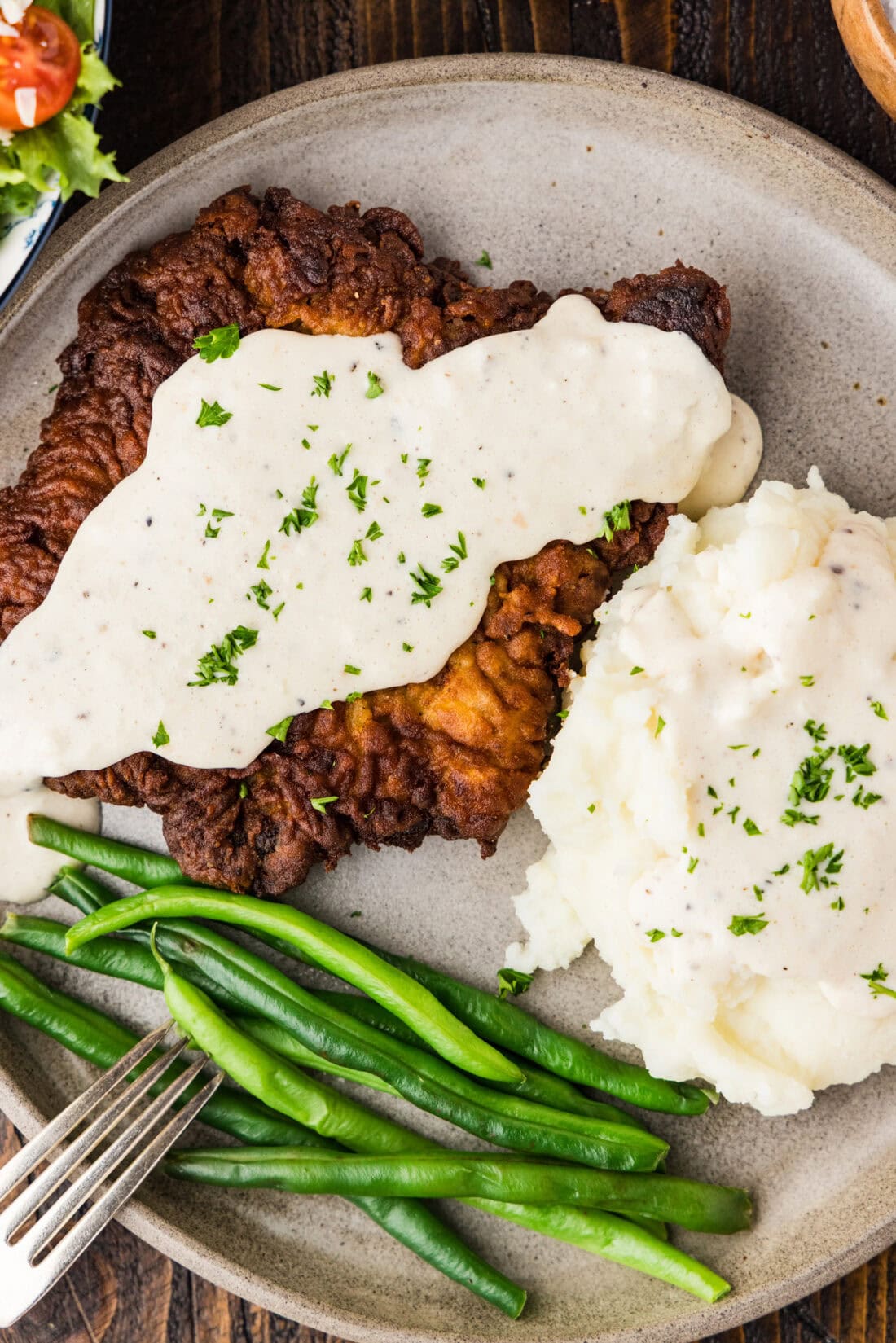 Close up photo of Chicken Fried Steak plated with mashed potatoes and green beans