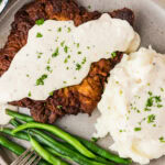 Close up photo of Chicken Fried Steak plated with mashed potatoes and green beans