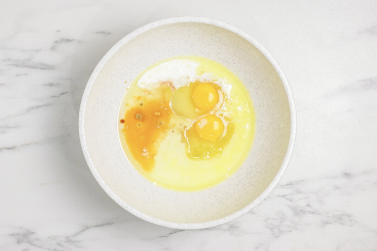 Sugar, eggs, milk, and vanilla in a mixing bowl