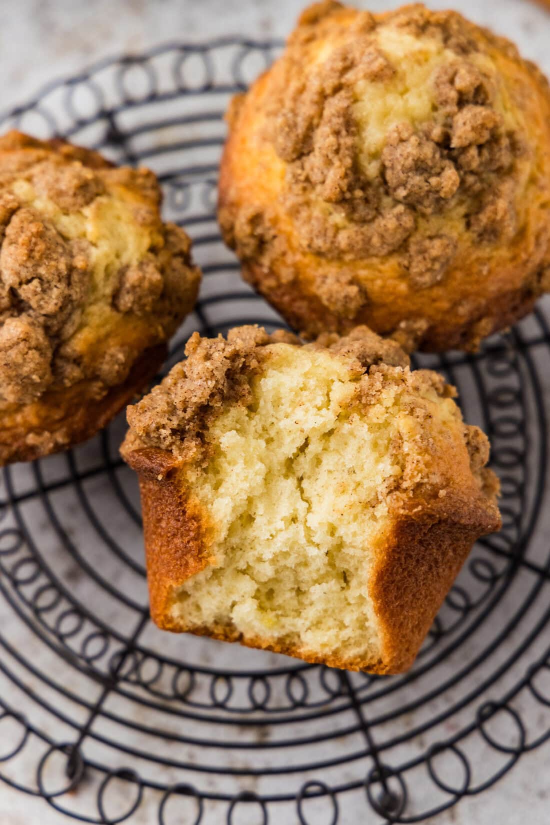 Cinnamon Streusel Muffins on a wire rack with a bite taken out of one