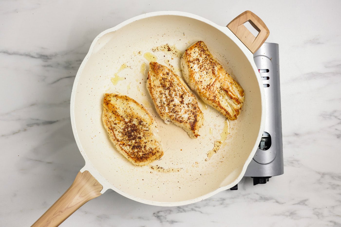 Chicken breasts cooked in a skillet with oil