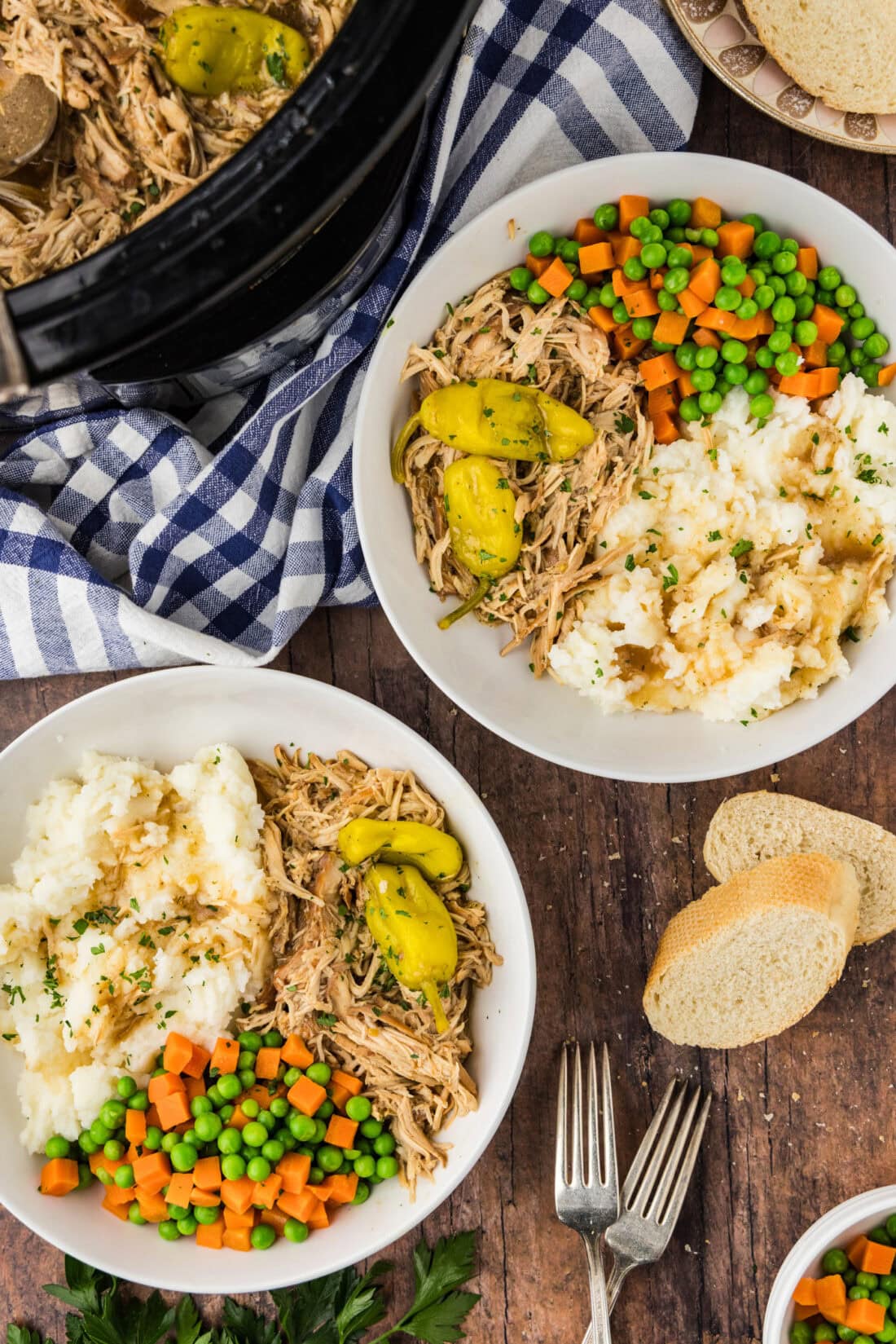 Two bowls of Mississippi Chicken with veggies and mashed potatoes on the side