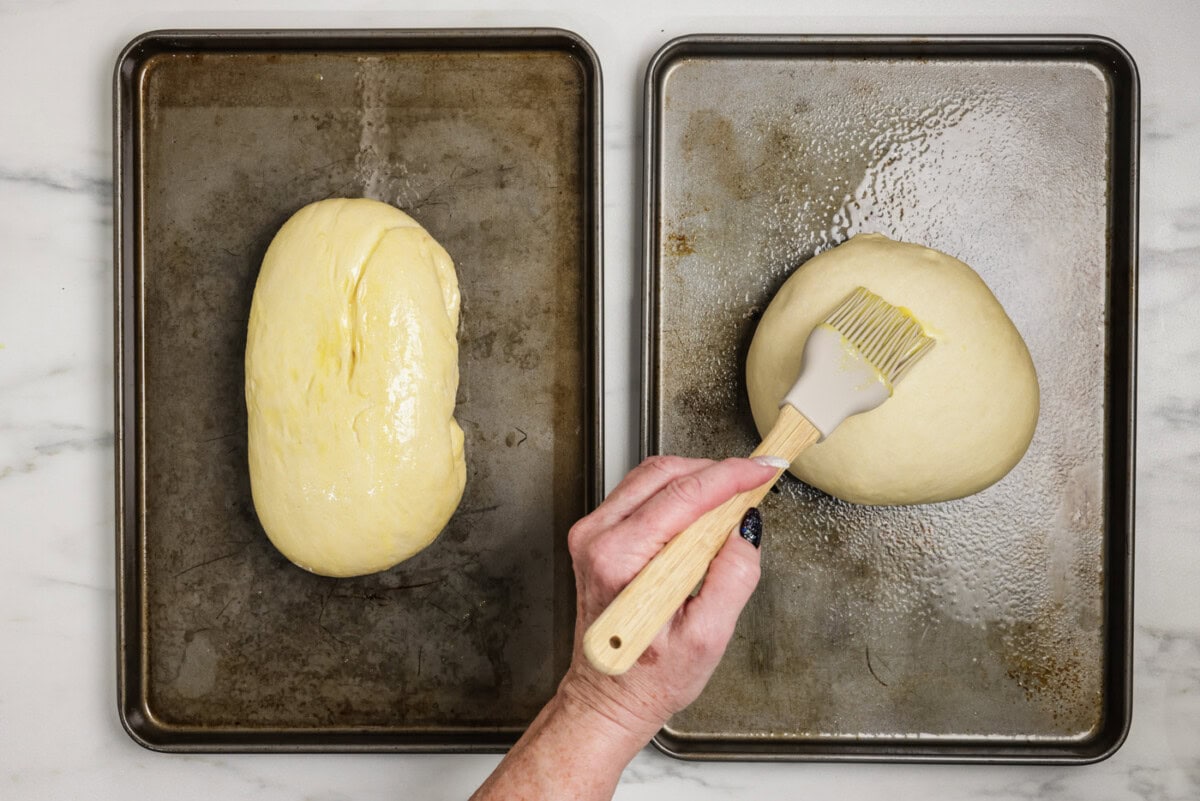 Brushing egg over bread dough on baking sheets