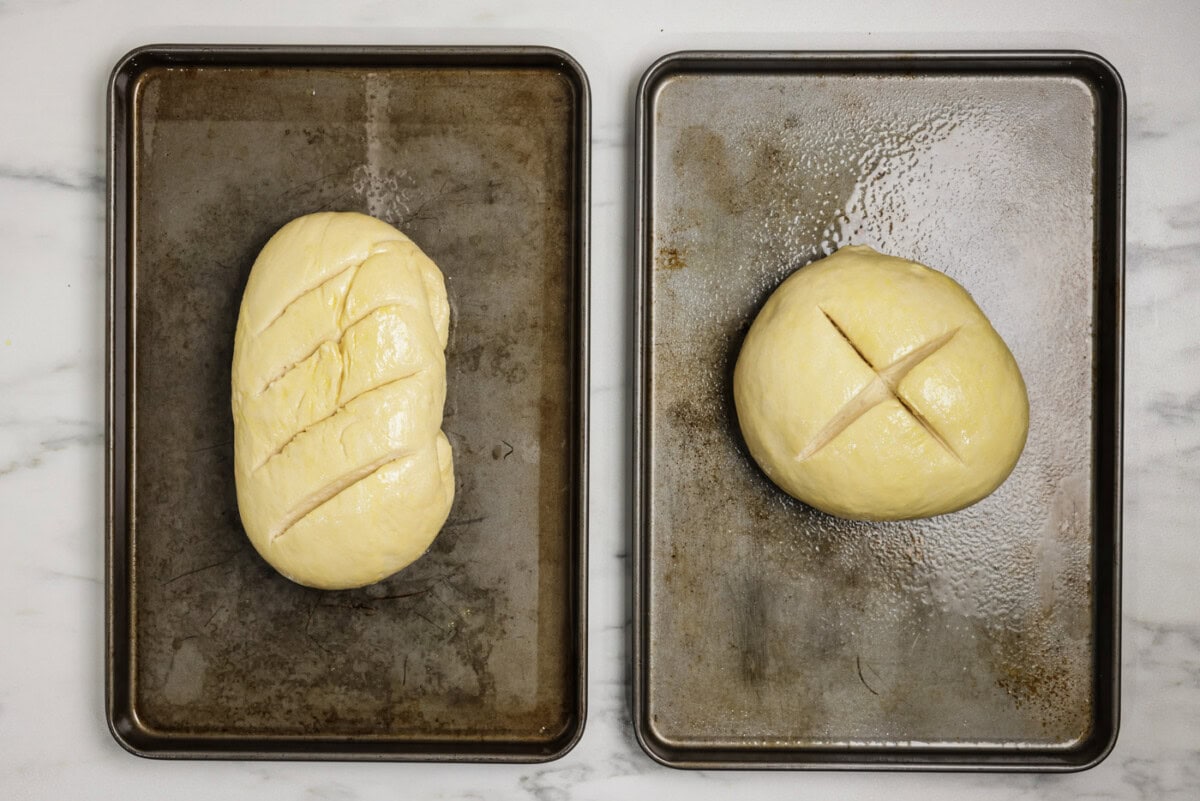 Overhead shot of scored bread dough loaves on baking sheets