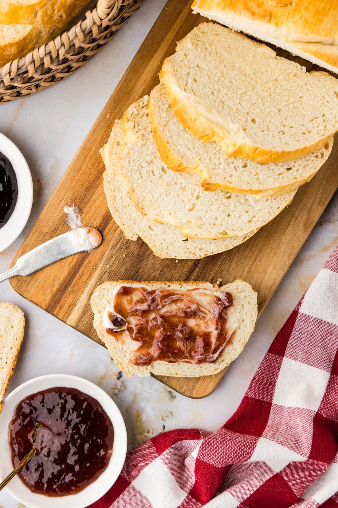One Hour Bread sliced on a wooden cutting board topped with butter and jam