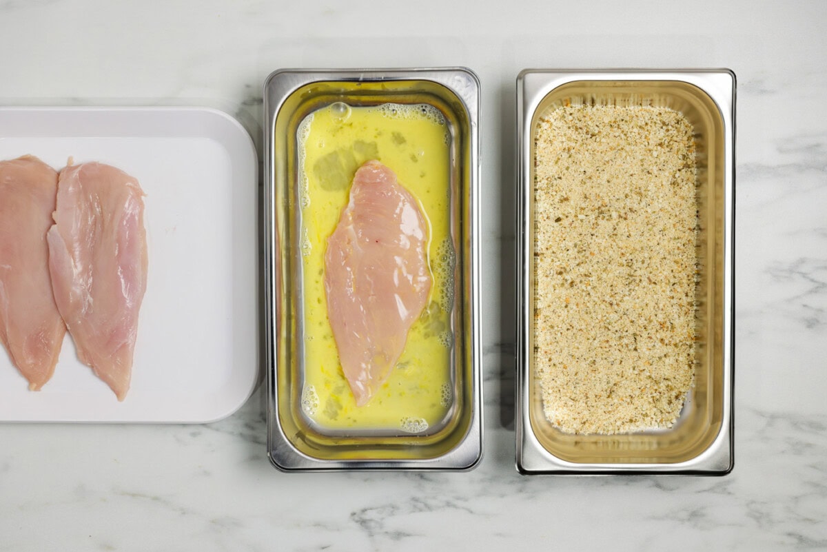 chicken breast in a breading tray with egg and water