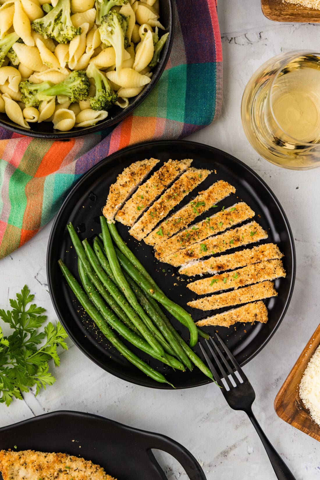 Sliced Parmesan Crusted Chicken on a plate with green beans