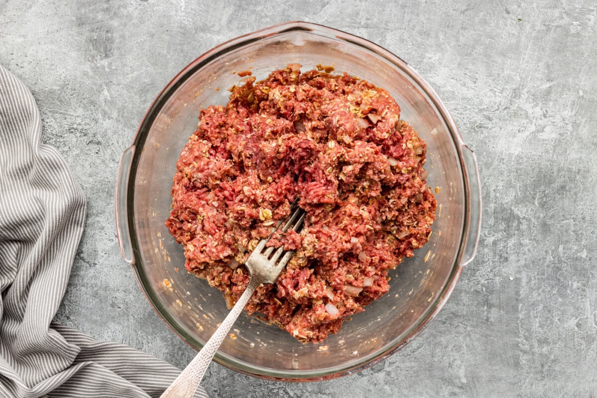 Fork in a bowl of combined meatloaf ingredients