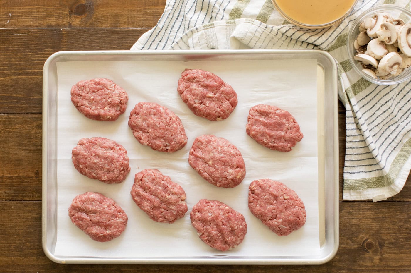 Salisbury steak patties on a parchment lined baking sheet