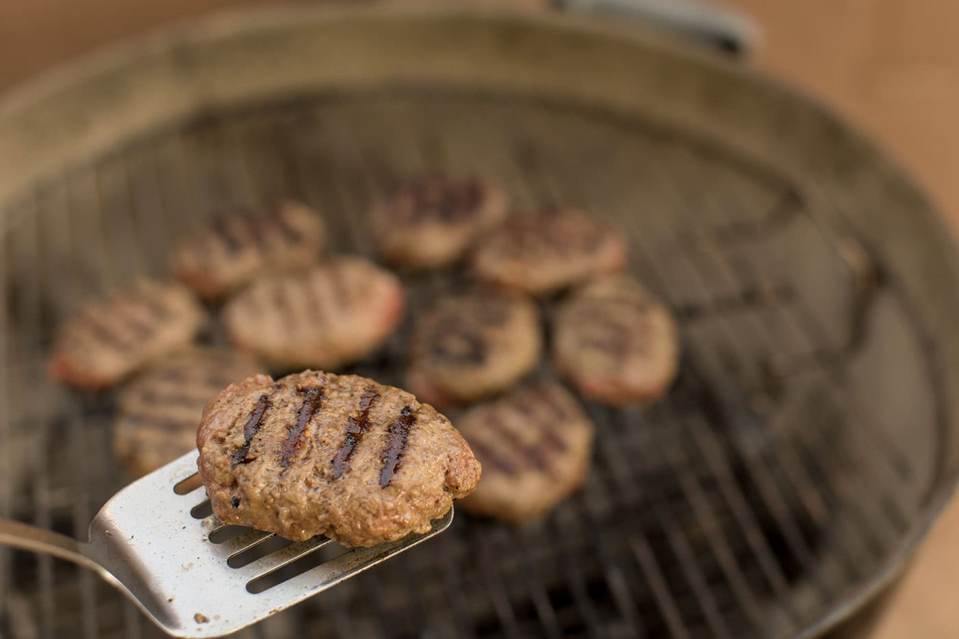 Spatula holding a salisbury steak patty with grill marks on it