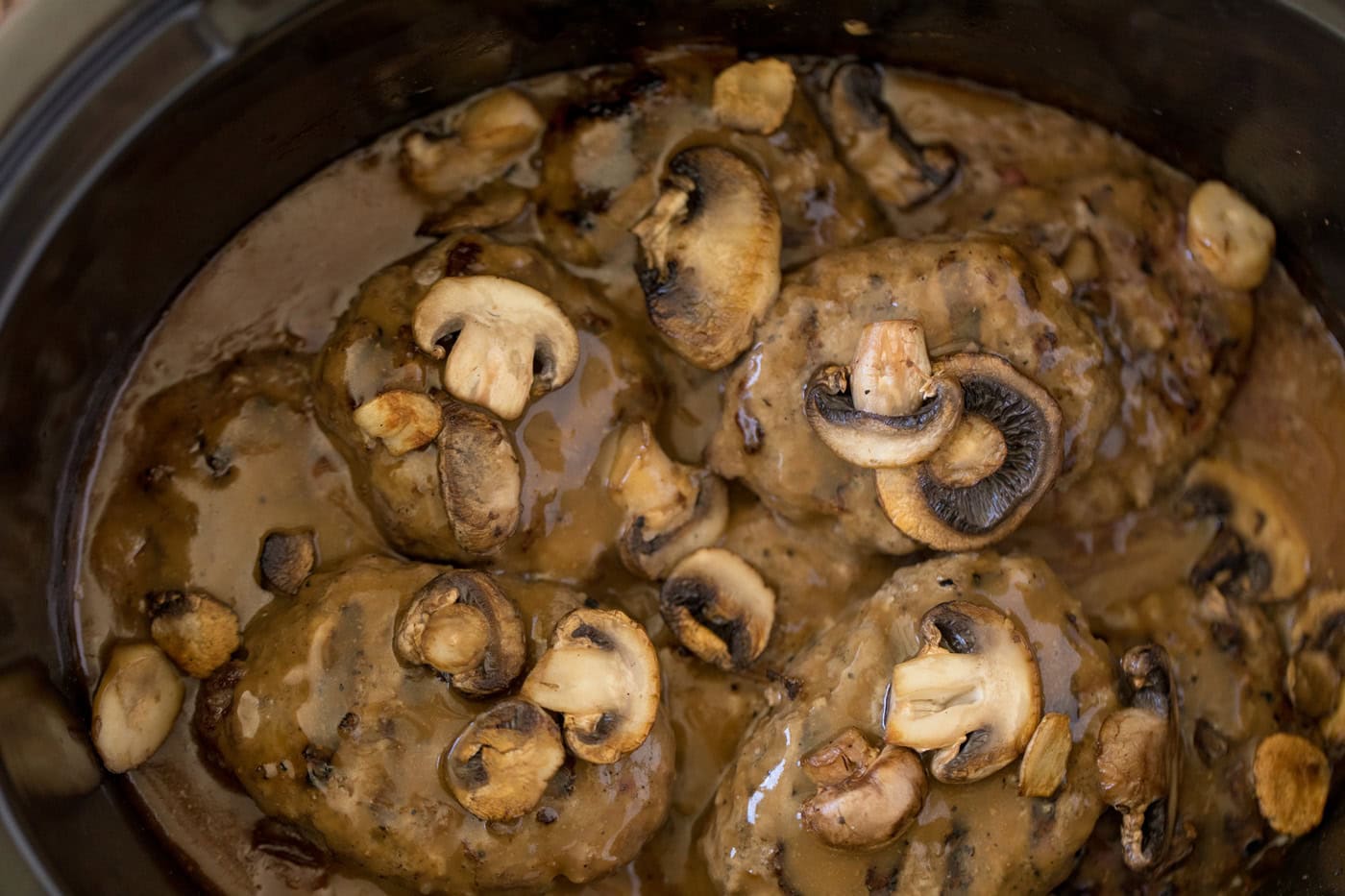 Mushrooms, gravy, and Salisbury steak patties in a slow cooker