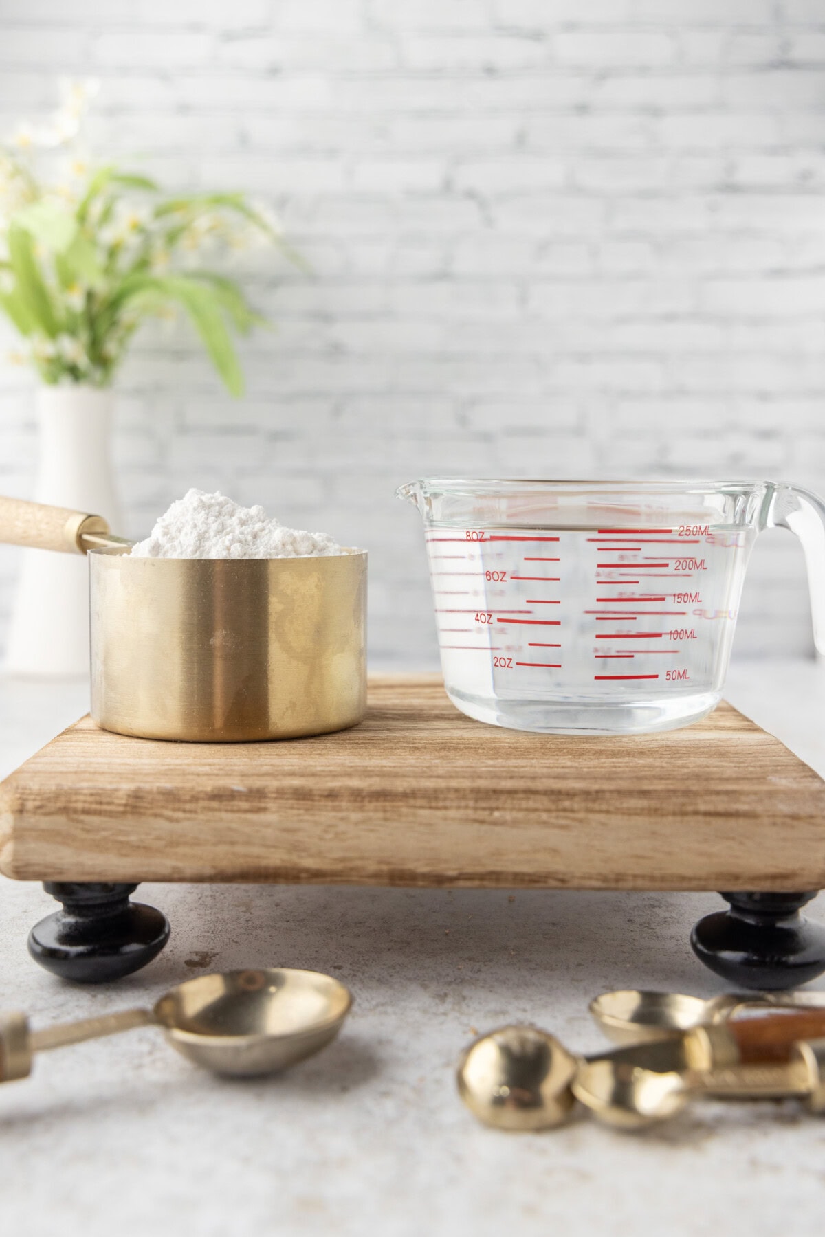 a dry measuring cup with flour next to a glass measuring cup with water