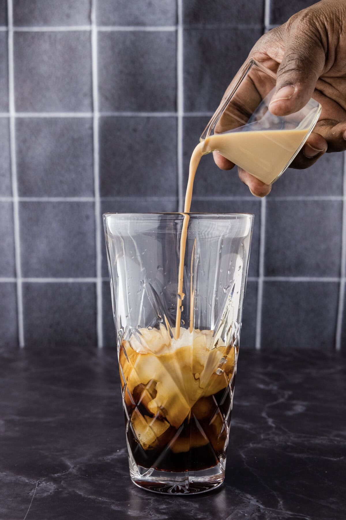 Hand pouring vodka into a cocktail shaker with Baileys and chocolate liqueur