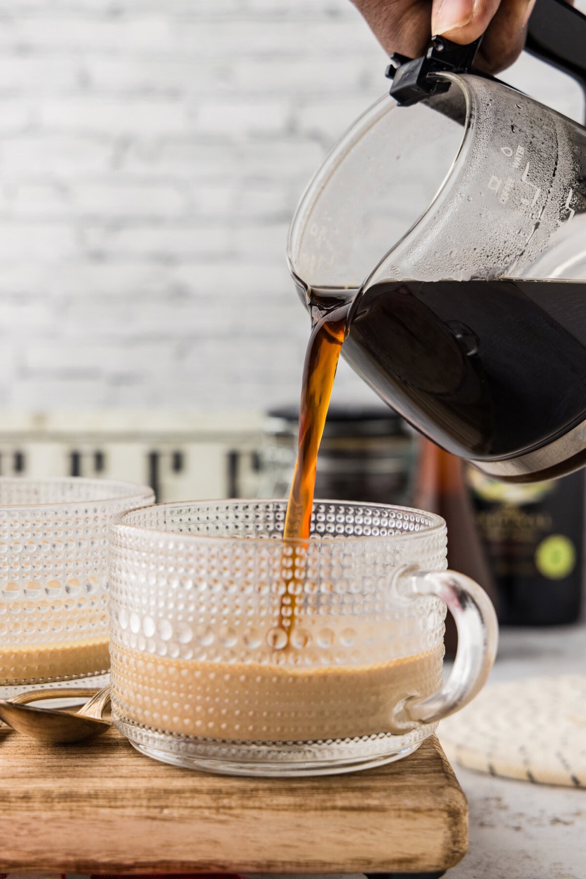 Pouring hot coffee into glass mug with Baileys