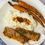2 slices of beef brisket and gravy with mashed potatoes and carrots