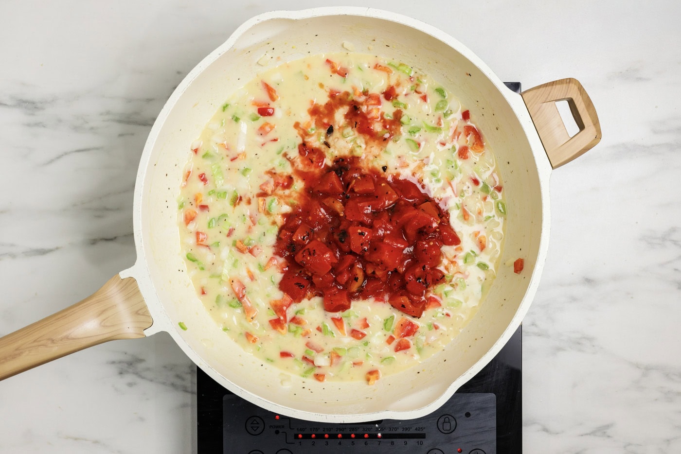 Canned tomatoes added to roux mixture in a skillet
